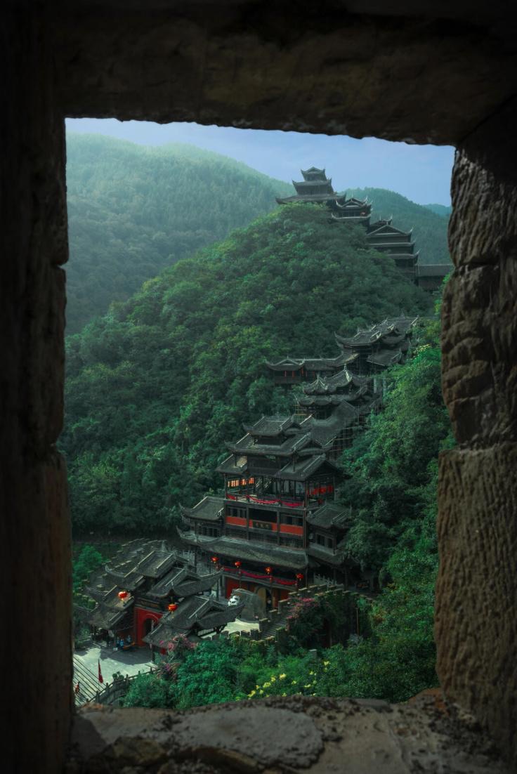 Layered mountain architecture at Chiyou Jiuli City framed by a stone window